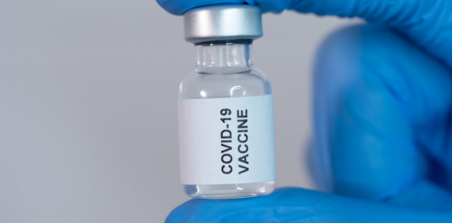 Covid-19 vaccine vial held by the gloved hand of a healthcare staff in the hospital